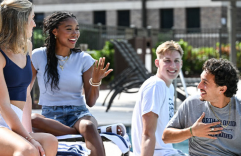 Four students sitting outside having a conversation