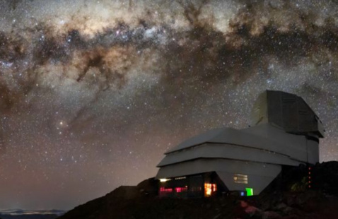 The Vera Observatory lit by a vibrant night sky.