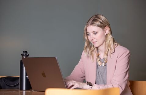 Woman sitting at a desk in front of a laptop. 