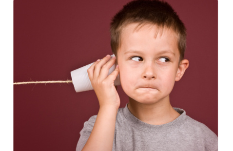 little boy holding a paper cup and string telephone to his ear.