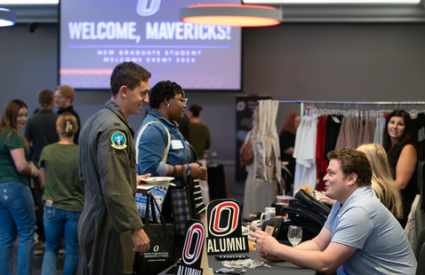Students visiting campus partner tables at a past open house