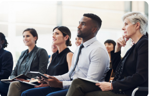 People dressed in business attire sit at conference.