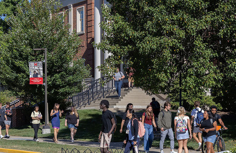 students walk on the sidewalk in front of benton Hall