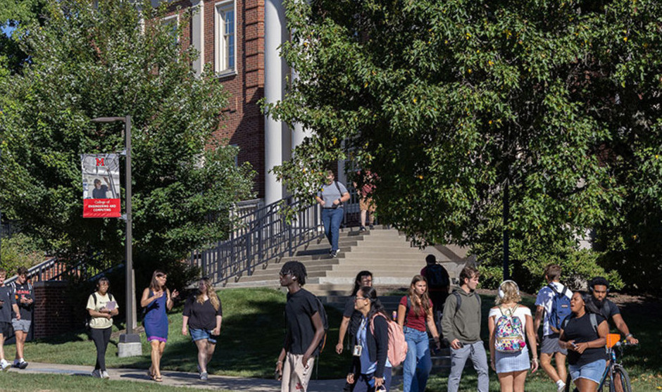 students walk on the sidewalk in front of benton Hall