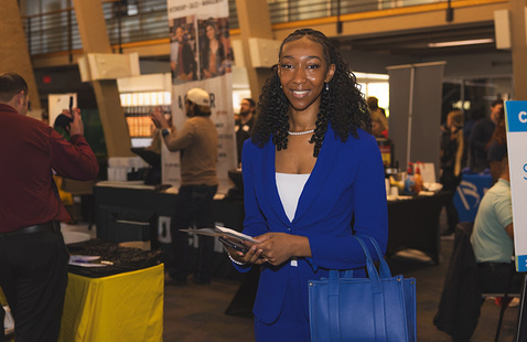 UWF student in professional attire attending an indoor career fair event.