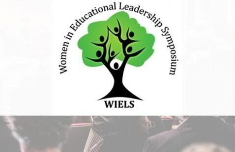 Logo for the Women in Educational Leadership Symposium (WIELS) featuring a stylized green tree with human figures forming the branches, centered on a blurred background of an auditorium audience attending a presentation. The text on the logo reads "Women's Educational Leadership Symposium, WIELS".