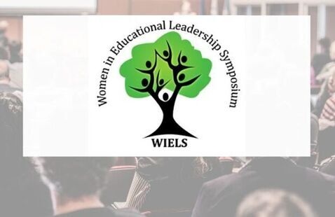 Logo for the Women in Educational Leadership Symposium (WIELS) featuring a stylized green tree with human figures forming the branches, centered on a blurred background of an auditorium audience attending a presentation. The text on the logo reads "Women's Educational Leadership Symposium, WIELS".