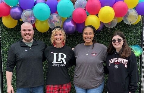 LR faculty and staff pose for camera against a wall of balloons