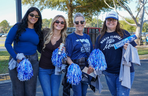 Four women with pom poms standing outside