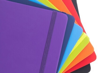 An array of small notebooks in all the colors of the rainbow.