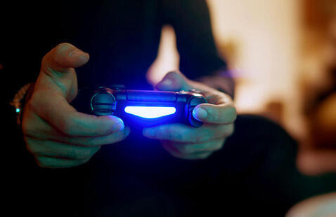 video game controller in hand with a blue glowing light