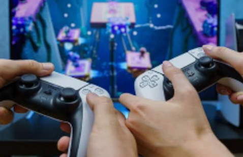 Image of hands holding PS5 controllers towards a screen.