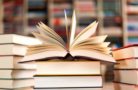 An open book on a pile of other books