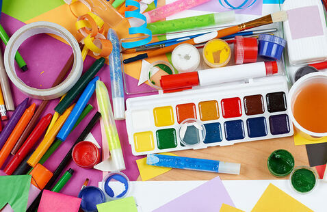 A collection of art supplies including water color paint, markers, and glitter