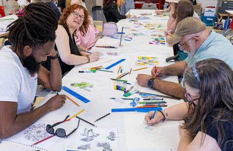 A group of people make art around a table