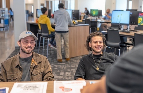 two male students laughing with a CNM employee in KW
