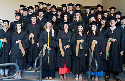 Sustainable Innovation MBA students stand in rows on stairs wearing graduation regalia