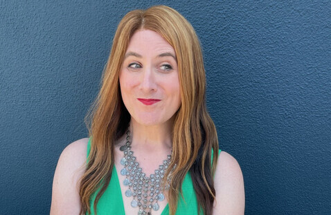A woman gives a playful look off camera in front of a blue background