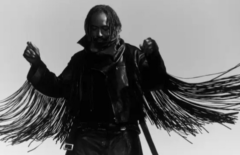 A man in shadows with long tassels on his arms 