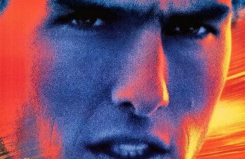 A adult man glares forward with bright flaring lights around him 