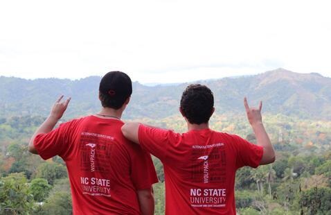 Two students wearing NC State Alternative Service Break T-shirts look at a mountain.