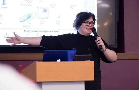 A smiling student presenting their research to an audience.