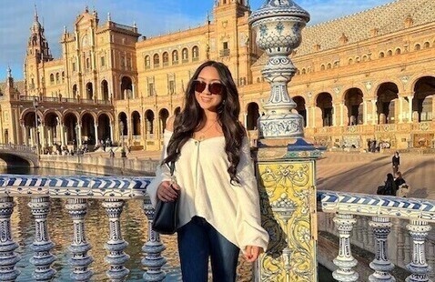Student studying abroad enjoys view from decorative bridge with historic building in background