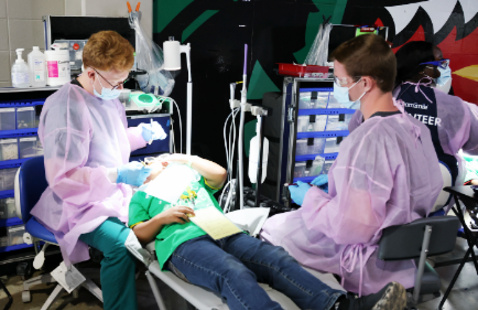Two dental students providing care to child patient at UAB and TeamSmile event