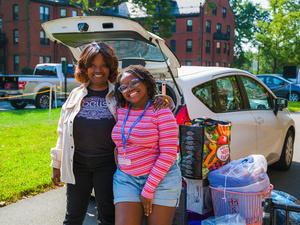A family duo smile for the camera with their moving packages behind them.