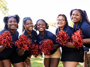 Smiling orientation leaders with red pompoms pose together.