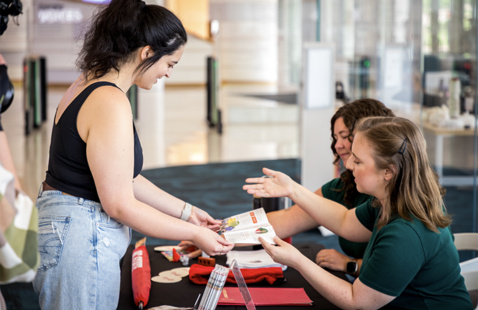 Two librarians showing a student a pamphlet.