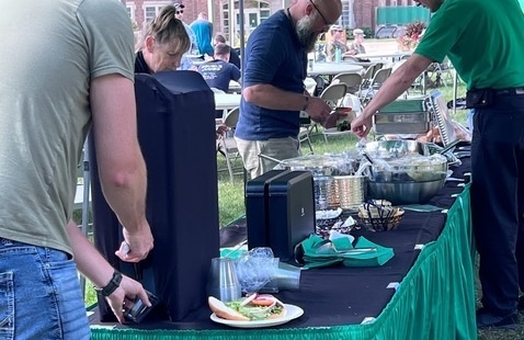 Picnic serving line with people grabbing from table