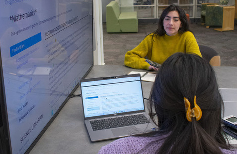 Two people sitting next to screens