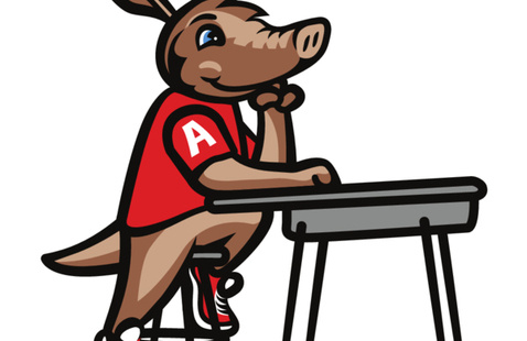 Cartoon Arty the aardvark, wearing a red shirt with a white A on the sleeve, sitting at a school desk