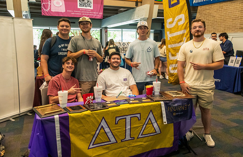 Six students around a fraternity table during an indoor fraternity and sorority meet and greet event.