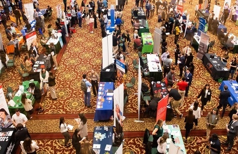 Potential employees mingle with potential employers at a job fair in a large conference space