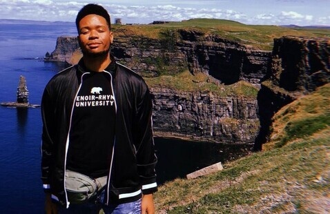 Student stands over hillside overlooking beautiful ocean view