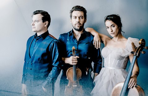 Two men and woman standing next to each other. One of the men has a violin and the woman is holding a cello.