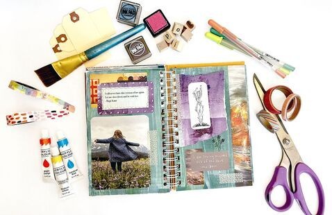 A journal surrounded by materials used to make it, including scissors