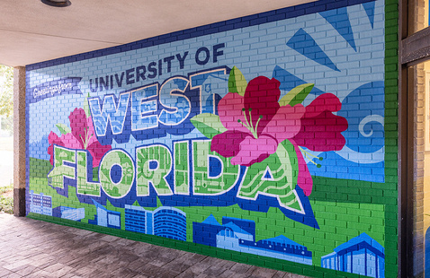Greetings from University of West Florida painted mural on an outdoor brick wall.