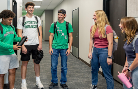 5 students talking in their residence hall hallway.