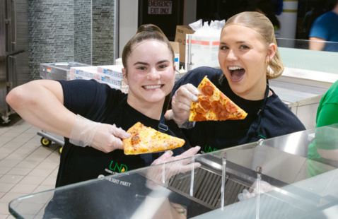 Two student staff posing with pizza during their event.
