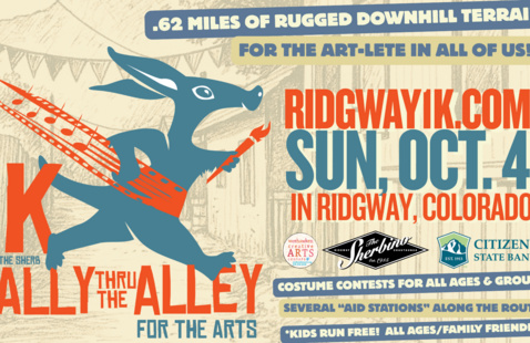 Promotional graphic for the Ridgway 1K Rally Thru the Alley for the Arts, featuring a stylized blue rabbit running with a paintbrush and musical notes. The family-friendly event takes place Sunday, October 4, in Ridgway, Colorado, along a 0.62-mile downhill course. The poster notes costume contests, aid stations, and free participation for children.