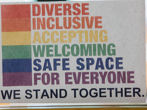Window signage in rainbow font: Diverse, inclusive, accepting, welcoming, safe space for everyone. we stand together.
