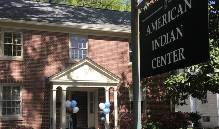 An exterior photograph of the American Indian center with a sign in the foreground.