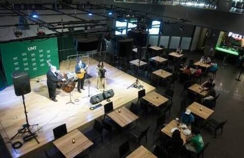 Photo of three individuals in the Syndicate playing music on a stage.
