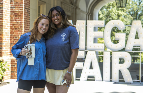 Two Students standing in front of large Mega Fair light up letters