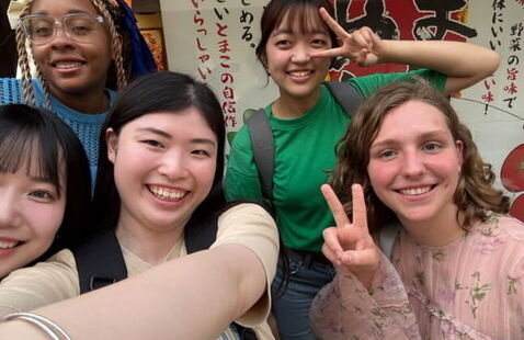 Students in Japan taking a selfie while holding up two fingers in the "peace" sign