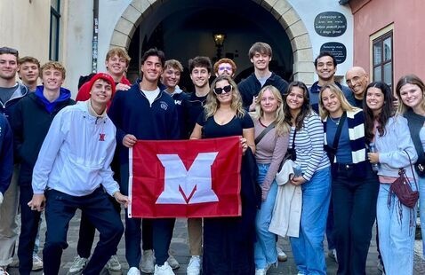 Group of students holding a red flag with a white "M" on it