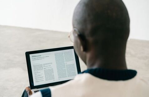 Person wearing glasses, reading an article on a laptop